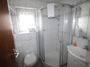 Ein Badezimmer mit Toilette, Duschkabine, Waschbecken und Spiegel.
