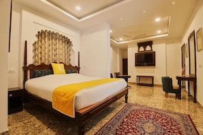 Habitación de hotel con cama, televisión, escritorio y una silla.