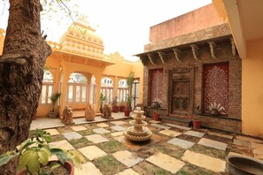 A courtyard with a fountain, potted plants, and traditional architecture. - Bloom Boutique Udaipur (Udaipur)