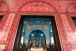 An ornate room with a high arched doorway, patterned walls, and a chandelier. - Bloom Boutique Udaipur (Udaipur)
