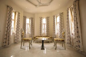 A room with a round table, ornate chairs, and floral curtains. - Bloom Boutique Udaipur (Udaipur)