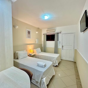 A hotel room with two beds, a television, an air conditioning unit, and a door. - Hotel Recanto dos Passaros de Sao Sebastiao (São Sebastião)