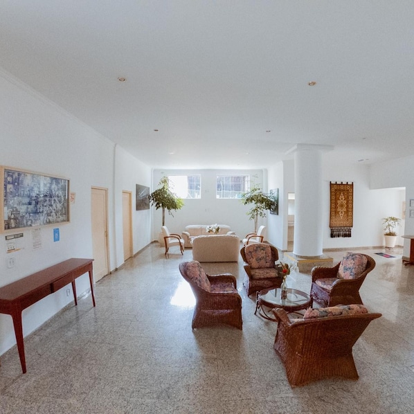 A spacious lobby with a high ceiling, a seating area with wicker furniture, a coffee table, and a large window providing natural light. - Hotel Recanto dos Passaros de Sao Sebastiao (São Sebastião)