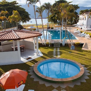 A swimming pool with a surrounding deck, lounge chairs, and umbrellas. - Hotel Recanto dos Passaros de Sao Sebastiao (São Sebastião)