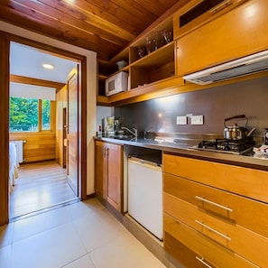Cocina compacta con muebles de madera, microondas, hervidor y lavavajillas.