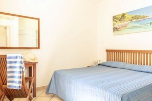 A bedroom with a bed, a chair, a table, a mirror, and a painting on the wall. - Argentario Giglio, Superior Two-Bedroom Apartment, Sleeps 4 (Albinia)
