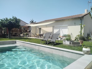 A swimming pool with lounge chairs, a patio area with a table and chairs, and a small garden with potted plants. - House with a private pool in the heart of Montélimar (Montélimar)