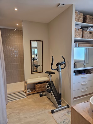 A modern bathroom with a shower, a bench, an exercise bike, and a storage cabinet. - House with a private pool in the heart of Montélimar (Montélimar)
