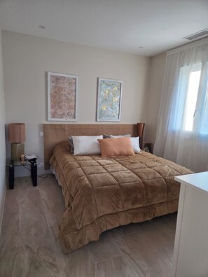 Una camera da letto con un letto, un comodino, una lampada e due opere d'arte incorniciate appese al muro.