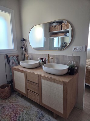 Un bagno con un mobiletto in legno, due lavabi, uno specchio grande e una finestra.