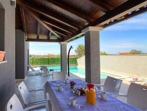 An outdoor dining area with a table set for two, overlooking a swimming pool and a view of the countryside. - Verde Comfortable Holiday Residence (Pula)