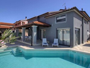 A modern house with a swimming pool, two lounge chairs, and a patio area. - Verde Comfortable Holiday Residence (Pula)