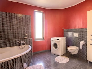 A bathroom with a bathtub, a washing machine, and a toilet. - Verde Comfortable Holiday Residence (Pula)