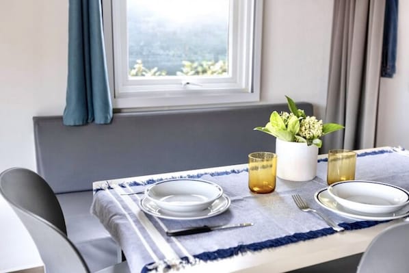 Een gedekte eettafel met borden, bestek en glazen, met uitzicht op het landschap buiten.
