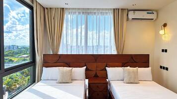 Une chambre d’hôtel avec deux lits, une grande fenêtre, un climatiseur et un ventilateur de plafond.