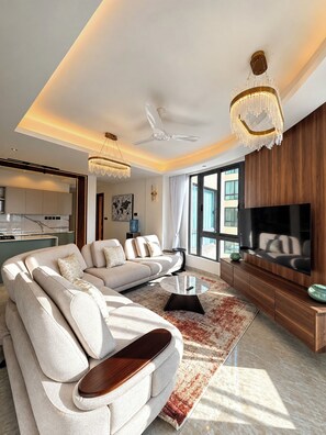 Een moderne woonkamer met een modulaire bank, een flatscreen televisie en een plafondventilator.