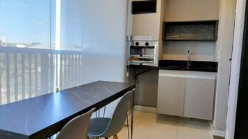 A compact kitchen with a dining area, including a table and chairs, a built-in oven, and a small countertop.