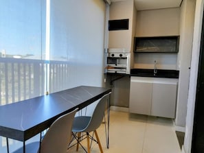A compact kitchen with a dining area, including a table and chairs, a built-in oven, and a small countertop. - Unique Residence (São José do Rio Preto)