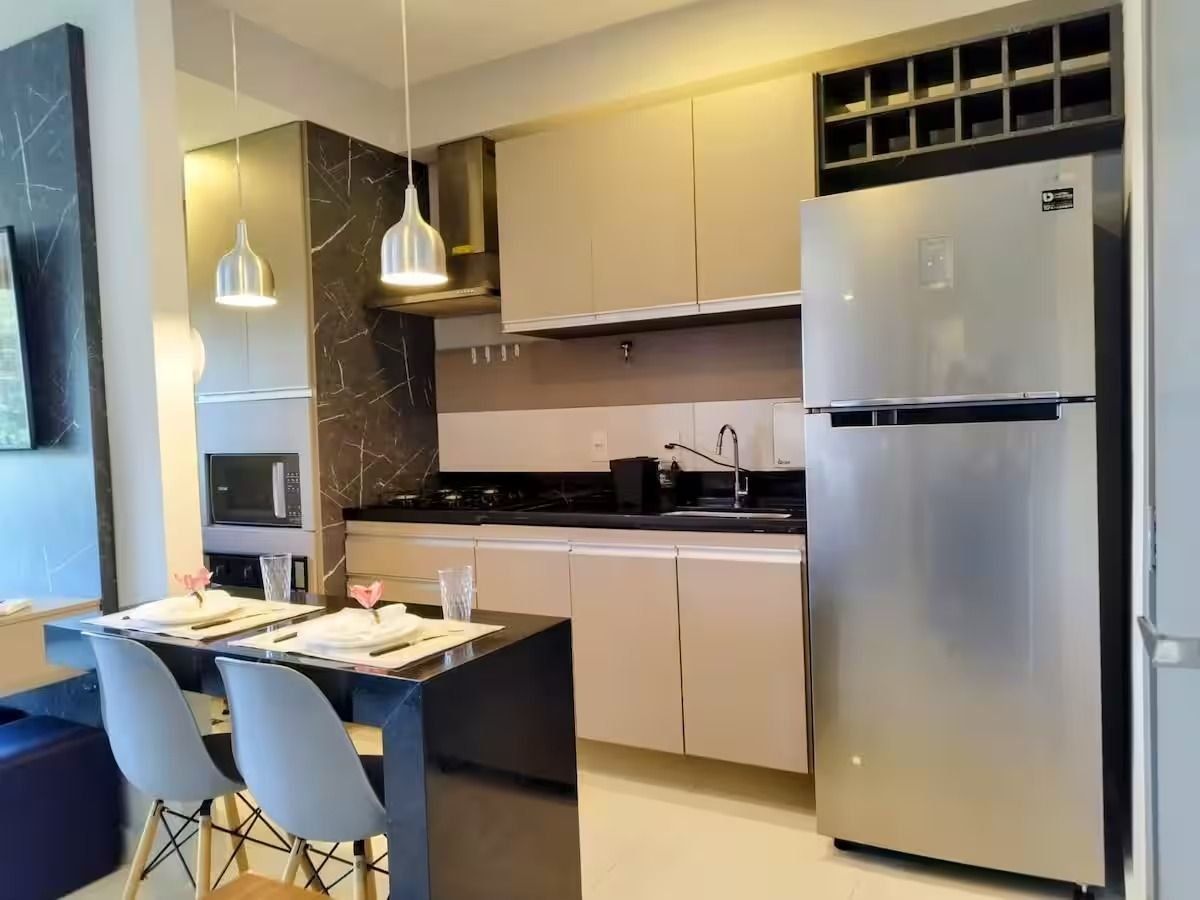 Een moderne keuken met een koelkast, fornuis en een eethoek met stoelen en een tafel.
