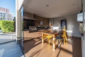 A modern kitchen with a built-in stove, a dining area with a wooden table and chairs, and a view of the outside. - Unique Residence (São José do Rio Preto)
