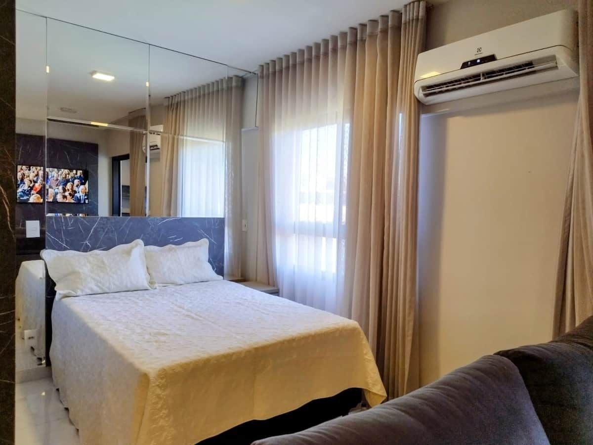 Habitación de hotel con cama, sofá, televisión y aire acondicionado.