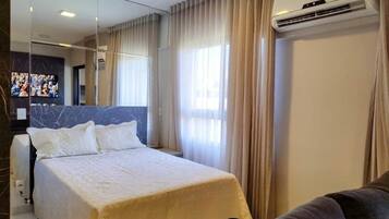 Habitación de hotel con cama, sofá, televisión y aire acondicionado.