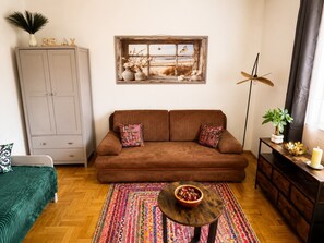 Een woonkamer met een bruine bank, een kleurrijk vloerkleed, een houten salontafel, een kast en een raam met uitzicht.