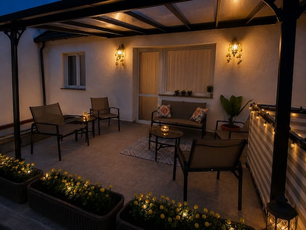 An outdoor patio with seating, a table, and decorative lighting.