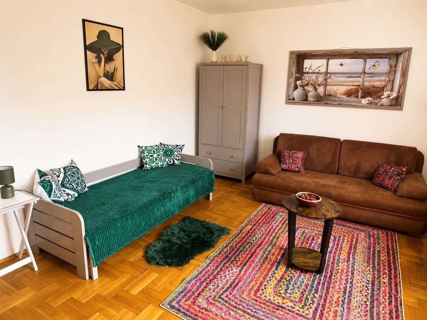 Una habitación con cama, sofá, armario, alfombra y un cuadro en la pared.