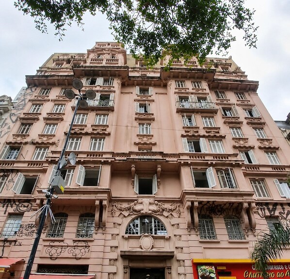 Un edificio de varios pisos con fachada simétrica, amplias ventanas y detalles arquitectónicos decorativos.