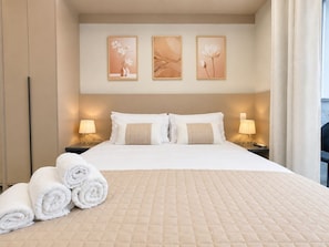 Ein Hotelzimmer mit einem großen Bett, zwei Nachttischlampen und drei an der Wand hängenden Bildern.