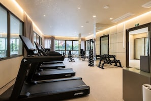 Ein Fitnessstudio mit Laufbändern, Hanteln und Trainingsgeräten.