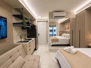A modern hotel room with a kitchenette, a bed, a sofa, and a TV. - Aconchego em Perdizes | Ao lado do Allianz Parque (São Paulo)