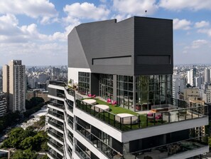 A modern building with a rooftop terrace featuring outdoor seating and a glass railing. - Ao lado da Av. Paulista | Metrô Paraíso | Moderno (São Paulo)