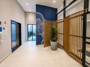 A modern hallway with a reception desk, a potted plant, and a large abstract mural on the wall. - Personalidade e Estilo | Ao lado do Sírio-Libanês (São Paulo)