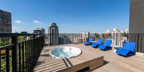 A rooftop terrace with a hot tub, blue lounge chairs, and a city view. - Personalidade e Estilo | Ao lado do Sírio-Libanês (São Paulo)