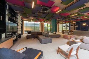 A modern interior with a sectional sofa, a flat-screen TV, and a bar area. - Praticidade a 1 minuto do Metrô República (Santa Ifigênia)