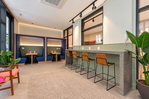 A modern hotel lobby with a bar area, seating arrangements, and a large potted plant. - Praticidade a 1 minuto do Metrô República (Santa Ifigênia)