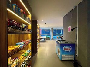 Innenansicht eines Supermarktes mit Regalen voller verschiedener Waren, einem Kühlregal von Nestlé und Blick durch das Fenster.