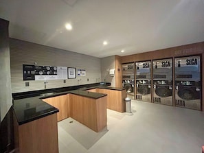 Eine moderne Küche mit Holzschränken und schwarzen Arbeitsplatten, einem Spülbecken und einer an der Wand befestigten Waschmaschine.