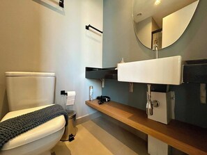Een moderne badkamer met toilet, wastafel en spiegel.