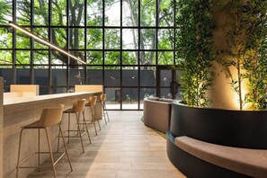 Een moderne bar met een lange toonbank, barkrukken en een zithoek met een gebogen bank.