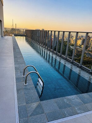 Ein Dachpool mit unendlicher Optik und Glasgeländer, der einen Blick auf die Stadt ermöglicht.