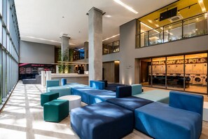 Eine moderne Hotelhalle mit Sitzbereichen, einer sichtbaren Wäscherei und einer großen Säule.