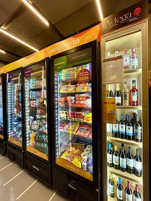 Vending machines stocked with snacks and beverages, and a refrigerated display case with bottled drinks. - Refúgio na Rua Augusta | Varanda e Ar Condicionado (São Paulo)
