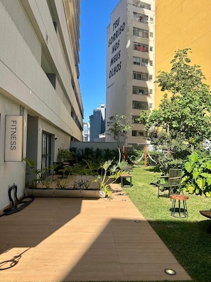 A courtyard with a wooden deck, potted plants, and outdoor furniture. - Refúgio na Rua Augusta | Varanda e Ar Condicionado (São Paulo)