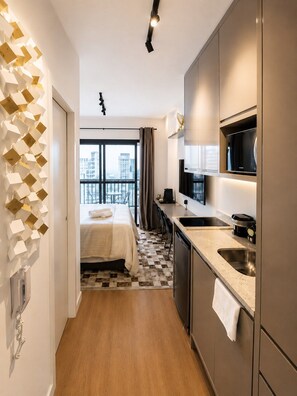 Ein modernes Hotelzimmer mit Bett, einer Küchenzeile, einem großen Fenster mit Stadtblick und einer einzigartigen geometrischen Wanddekoration.