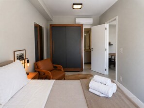 A hotel room with a bed, a chair, a wardrobe, and a bathroom visible through an open door. - Onde a Privacidade Encontra a Elegância República (Santa Ifigênia)
