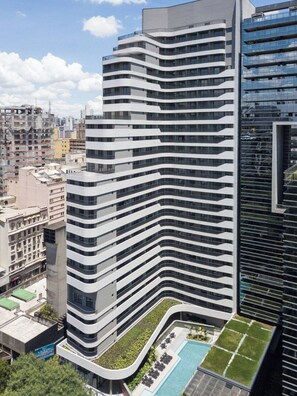 A modern high-rise building with a curved facade, multiple balconies, and a rooftop pool area. - Onde a Privacidade Encontra a Elegância República (Santa Ifigênia)