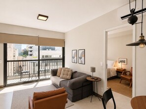 A modern living room with a sofa, chairs, a small table, and a balcony with a railing. - Onde a Privacidade Encontra a Elegância República (Santa Ifigênia)